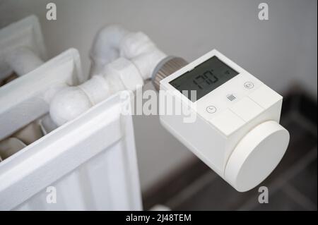 Modernes intelligentes Heizventil mit Thermostat, das an einen alten Heizkörper für Warmwasserbereitung nachgerüstet wurde, um die Raumtemperatur zu regeln Stockfoto