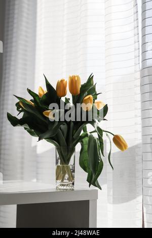 Schöne gelbe Tulpen in Glasvase zu Hause. Bunte Frühlingsblumen Stockfoto
