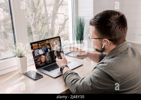 Rückansicht Porträt eines glücklichen Geschäftsmannes, der Kollegen die Momente eines neuen Projekts auf einem Videotreffen am Schreibtisch im Heimbüro erklärt.Styl Stockfoto