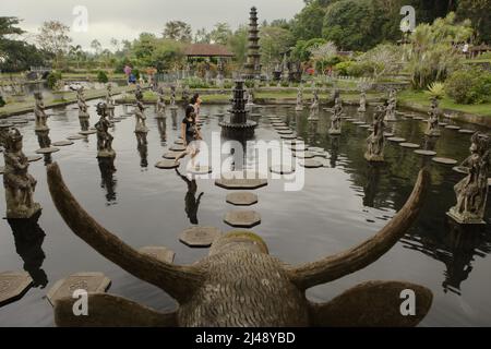 Besucher, die auf steinernen Fußstapfen am Tirta Gangga Wasserpalast in Karangasem, Bali, wandeln. Das Tirta Gangga (tirta bedeutet „heiliges Wasser“; Gangga bezieht sich auf den Ganges in Indien) wurde auf der Grundlage der Überzeugung erbaut, dass Wasser heilig ist, und war ein ehemaliger königlicher Palast des Königreichs Karangasem. Stockfoto