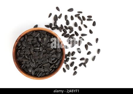 Schwarze Sonnenblumenkerne in Holzschale isoliert auf weißem Hintergrund mit Platz für Text, Draufsicht auf Haufen gerösteter, ungeschälter Samen Stockfoto
