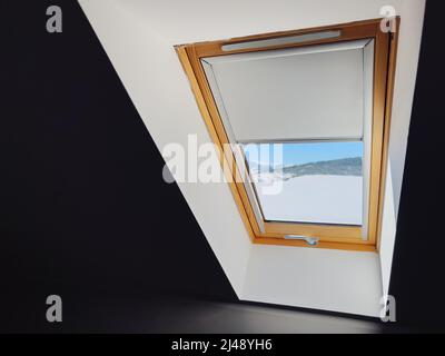 Dachfenster im Winter vom dunklen Innenraum aus gesehen Stockfoto