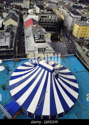 Linz, Österreich - 06. Juli 2013: Luftaufnahme eines gestreiften Zirkuszeltes auf einem Dach mit Stadtbild Stockfoto