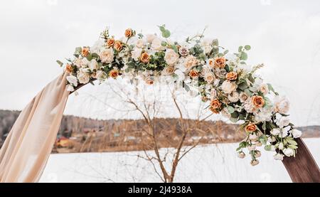 Hochzeit Rundbogen mit Blumen und Stoff im Frühjahr oder Winter. Der Ort der Braut und des Bräutigams für die Zeremonie in der Natur Stockfoto