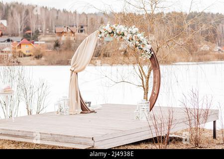 Hochzeit Rundbogen mit Blumen und Stoff im Frühjahr oder Winter. Der Ort der Braut und des Bräutigams für die Zeremonie in der Natur Stockfoto