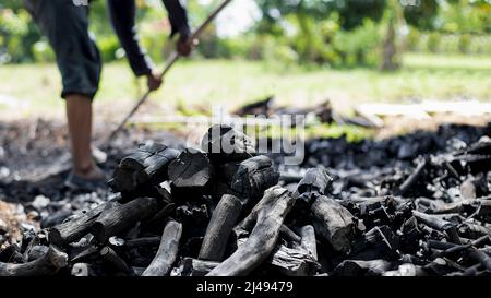 Die Bauern verbrennen Holzkohle aus Holz, das von der Farm abgeschnitten ist. Stockfoto