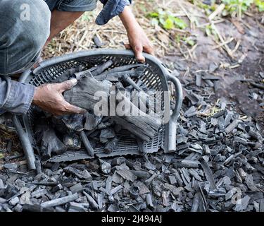 Die Bauern verbrennen Holzkohle aus Holz, das von der Farm abgeschnitten ist. Stockfoto