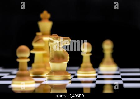 Nahaufnahme von Schachfiguren auf einer reflektierenden Spiegelfläche mit einem schlichten schwarzen Hintergrund Stockfoto