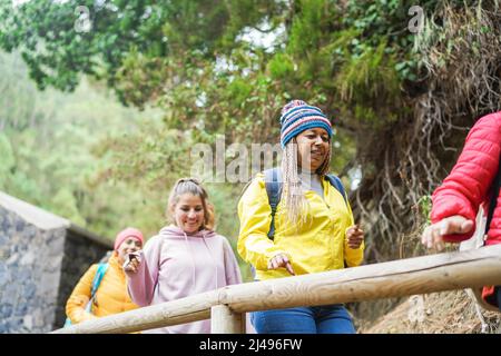 Multirassische Frauen, die beim Trekking-Tag im Bergwald Spaß an der Erkundung der Natur haben - Fokus auf afrikanisches Seniorengesicht Stockfoto