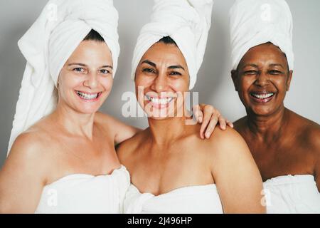 Reife Frauen lachen zusammen, während sie Körperhandtücher tragen - Fokus auf das Gesicht der Frau in der Mitte Stockfoto