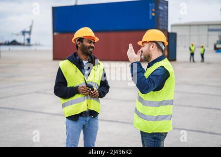 Arbeiter, die Schiffscontainer im Industriehafen im Freien kontrollieren - Fokus auf die rechte Hand Stockfoto