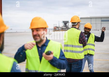 Arbeiter, die Schiffscontainer im Industriehafen im Freien kontrollieren - Fokus auf das indische Männergesicht Stockfoto