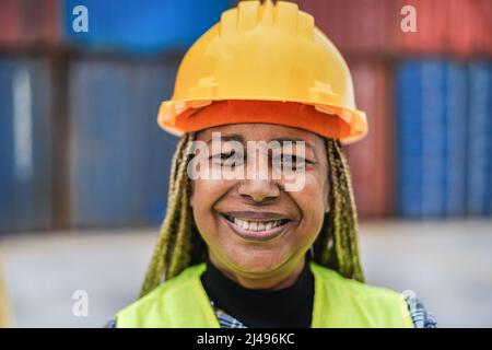 Arbeiter afrikanische ältere Frau lächelt vor der Kamera mit Industriehafen im Hintergrund - Hauptfokus auf Nase Stockfoto