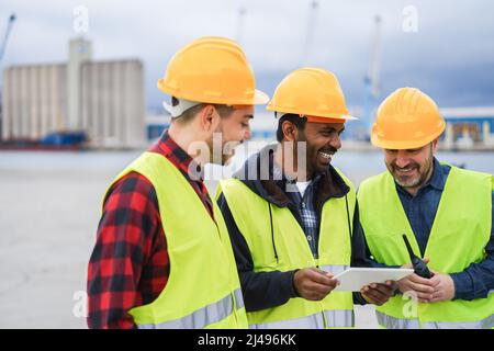 Arbeiter, die Schiffscontainer am Industriehafen im Freien mit Tablet kontrollieren - Fokus auf indisches Männergesicht Stockfoto