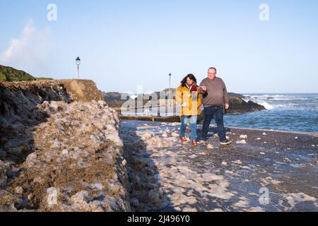 Schaumstoff, der durch den jüngsten Sturm und starke Winde produziert wurde, säumt die Wände des Ballintoy Harbour in Co. Antrim, Nordirland. Stockfoto