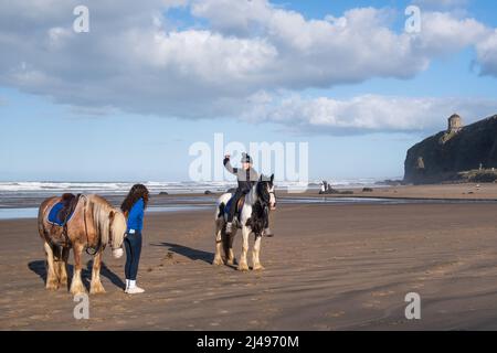 Reiter am Strand von Downhill in Co. Londonderry an der Nordküste von Nordirland. In der Mitte der Strecke ein Paar, das ihre Hochzeit hat Stockfoto