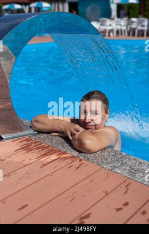 Geothermisches Spa-Zentrum. Wunderschöne Frau entspannt sich unter dem Wasserfall mit Hydromassage im tropischen Resort auf dem Meer Stockfoto