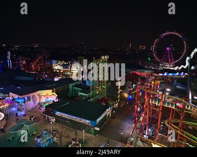 Luftaufnahme über den Vergnügungspark Wurstelprater im Dunkeln in Wien, Österreich mit beleuchteten Fahrgeschäften inklusive Achterbahnen und Riesenrad. Stockfoto