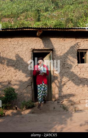 Genevieve, Manishimwe, 40, Dorf Nyange, Murambi-Zelle, Gakenke disrict. Ihr Mann wurde beim Völkermord getötet, sie hat vier Kinder, darunter Diane, 7 Jahre alt. Sie ist HIV-positiv. Bevor sie sich dem Programm anschloss, zog sie von Ort zu Ort, weil sie kein Haus hatte und oft hungrig war. Mit dem Erlös ihrer Landwirtschaft nach dem Training aus dem Programm hat sie sich nun ein Haus gebaut. Sie kaufte drei Parzellen Land, eine Kuh und zwei Schweine. Foto von Mike Goldwater Stockfoto