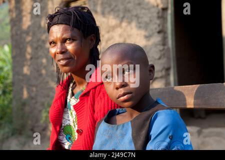 Genevieve, Manishimwe, 40, Dorf Nyange, Murambi-Zelle, Gakenke disrict. Ihr Mann wurde beim Völkermord getötet, sie hat vier Kinder, darunter Diane, 7 Jahre alt. Sie ist HIV-positiv. Bevor sie sich dem Programm anschloss, zog sie von Ort zu Ort, weil sie kein Haus hatte und oft hungrig war. Mit dem Erlös ihrer Landwirtschaft nach dem Training aus dem Programm hat sie sich nun ein Haus gebaut. Sie kaufte drei Parzellen Land, eine Kuh und zwei Schweine. Foto von Mike Goldwater Stockfoto