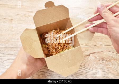 Gebratene japanische Yakisoba-Nudeln schneiden Schweinespeck und Kohl in einer Schachtel und essen mit Holzstäbchen Stockfoto