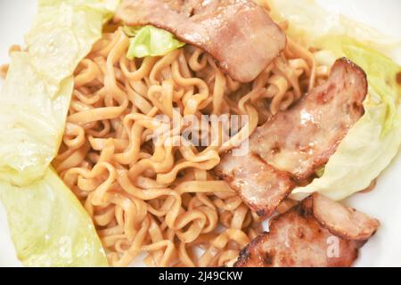 Gebratene japanische Yakisoba-Nudeln schneiden Schweinespeck und Kohl auf den Teller Stockfoto