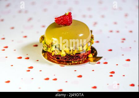 Selbstgebackene Avocado-Torte mit Sahnehäubchen, süßer Creme und Nüssen auf weißem Hintergrund mit Herzen, Nahaufnahme Stockfoto