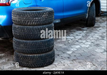Satz von Winterreifen neben dem Auto im Radservice, das Konzept des saisonalen Reifenwechsels Stockfoto