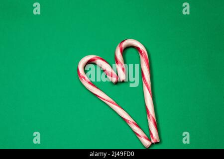 Herz mit Zuckerstöcken auf grünem Hintergrund Stockfoto