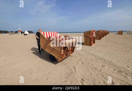 13. April 2022, Schleswig-Holstein, Travemünde: Ein Mitarbeiter eines Liegestuhlvermieters stellt am Strand vor der Travemünde-Promenade Liegestühle auf. Foto: Christian Charisius/dpa Stockfoto