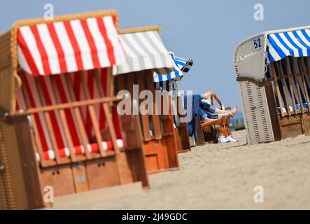 13. April 2022, Schleswig-Holstein, Travemünde: Zwei Gäste liegen in einer Liege am Strand vor der Promenade von Travemünde und genießen die Sonne. Foto: Christian Charisius/dpa Stockfoto