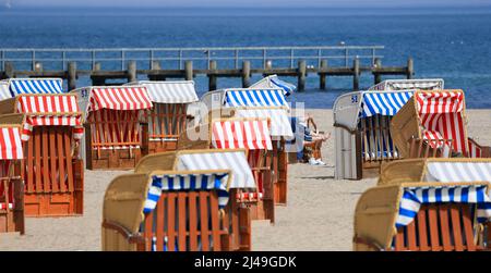 13. April 2022, Schleswig-Holstein, Travemünde: Gäste liegen in Strandliegen vor der Promenade von Travemünde und genießen die Sonne. Foto: Christian Charisius/dpa Stockfoto