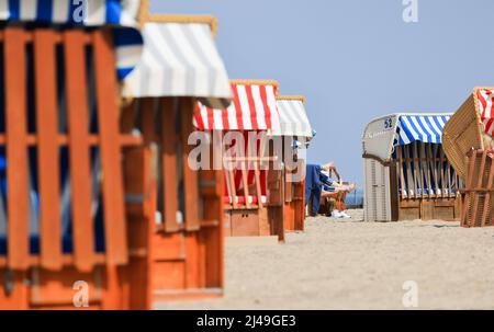 13. April 2022, Schleswig-Holstein, Travemünde: Zwei Gäste liegen in einer Liege am Strand vor der Promenade von Travemünde und genießen die Sonne. Foto: Christian Charisius/dpa Stockfoto