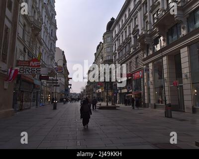 Blick auf die beliebte Einkaufsstraße Kärntner Straße in der Altstadt von Wien, Österreich am bewölkten Tag mit Menschen, Geschäften und alten Gebäuden. Stockfoto