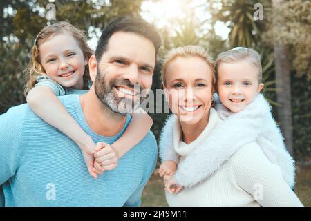 Liebe so mächtig wie deine Eltern. Aufnahme eines Paares mit ihren beiden Töchtern, die zusammen in einem Park posieren. Stockfoto