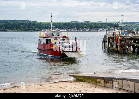 Fähre, die am Nigg Ferry Terminal ankommt, mit altem Balintraid Pier im Hintergrund – Nigg, Easter Ross Peninsula, Ross und Cromarty, Highland, Schottland, VEREINIGTES KÖNIGREICH Stockfoto