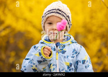 Wunderschönes Kind, Kleinkind, mit rosa Papierblume, handgefertigt für die Mutter zum Muttertag Stockfoto