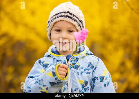 Wunderschönes Kind, Kleinkind, mit rosa Papierblume, handgefertigt für die Mutter zum Muttertag Stockfoto