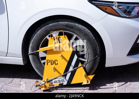 Eine Nahaufnahme eines weißen Autorads, das durch eine Radsperre blockiert wurde, weil das Parken illegal war. Selektiver Fokus. Stockfoto