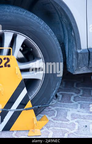 Eine gelbe Reifenklemme an einem Reifen. Strafe und Geldstrafe für unsachgemäßes Parken. Stockfoto