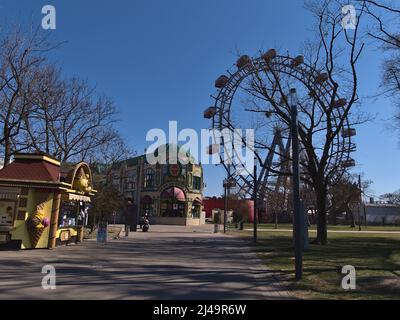 Schöne Aussicht auf den Eingang des Vergnügungsparks Wurstelprater in Wien, Österreich mit dem berühmten Riesenrad an sonnigen Tagen im Frühling. Stockfoto