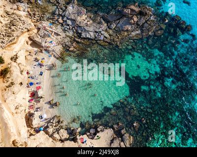 Es Caló d´es mort cala Strand, Luftaufnahme, Sommer Besucher liegen auf einer Bucht mit roten Klippen und Felsen in vor türkisfarbenem Wasser, Formentera Ba gesäumt Stockfoto