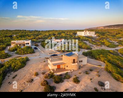 Apartments und typische Heus und Luftaufnahme in der Sonnenuntergangszeit an einem berühmten Strand von Plata de Mijorn, Formentera (Balearen). Stockfoto