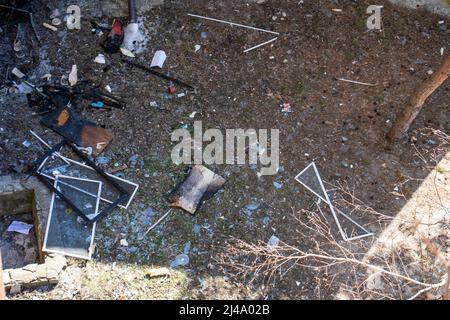 Teile der Fenster hängen an Ästen und liegen auf dem Boden. Die Luftwaffe der russischen Armee bombardierte zivile Objekte. Raketenangriff. Krieg Russlands Stockfoto