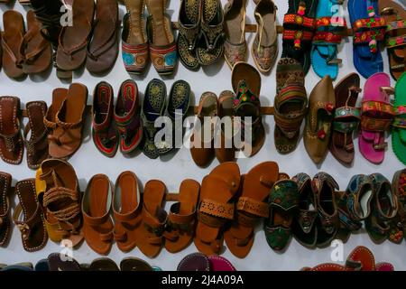 Zum Verkauf stehen zwei bunte Männer- und Frauenschuhe von Rajasthani. Jaisalmer, Rajasthan, Indien. Stockfoto