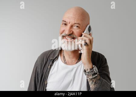 Kahlköpfiger europäischer Mann mit Bart, der über ein Mobiltelefon spricht, das auf weißem Hintergrund isoliert ist Stockfoto
