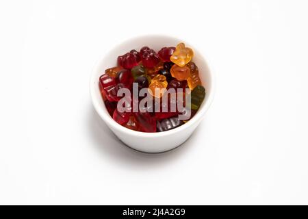 Bunte Gummikandys in einer weißen Tasse auf weißem Hintergrund Stockfoto