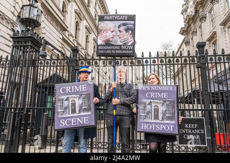 LONDON, GROSSBRITANNIEN. 13 April, 2022 . Demonstranten halten Plakate vor der Downing Street, auf denen der Rücktritt von Premierminister Boris Johnson wegen Party- und Sperrparteien gefordert wird. Die Met Police hat nach einer Untersuchung durch Scotland Yard Premierminister Boris Johnson und Kanzler Rishi Sunak wegen des Brechens von Sperrregeln und der Durchführung illegaler Parteiversammlungen in der Downing Street während strenger Beschränkungen durch das Coronavirus eine feste Sanktionsmitteilung herausgegeben.Quelle: amer ghazzal/Alamy Live News Stockfoto