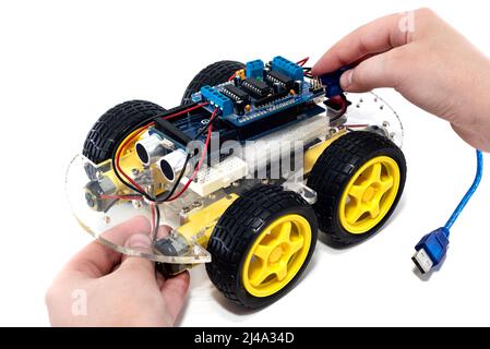 Hände halten programmierbare Roboterauto mit Hindernisvermeidung und Linie folgenden Fähigkeit, isoliert auf weißem Hintergrund mit Clipping-Pfad. Auto auf einem m Stockfoto