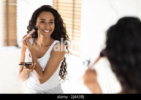 Schöne Junge Frau Blick Auf Spiegel Und Tun Tägliche Make-Up Im Badezimmer Stockfoto